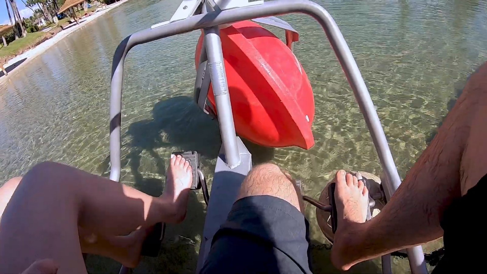 Bare feet on the pedals of a pedal-powered aqua cycle over shallow water in the lagoon at Hilton Waikoloa Village.