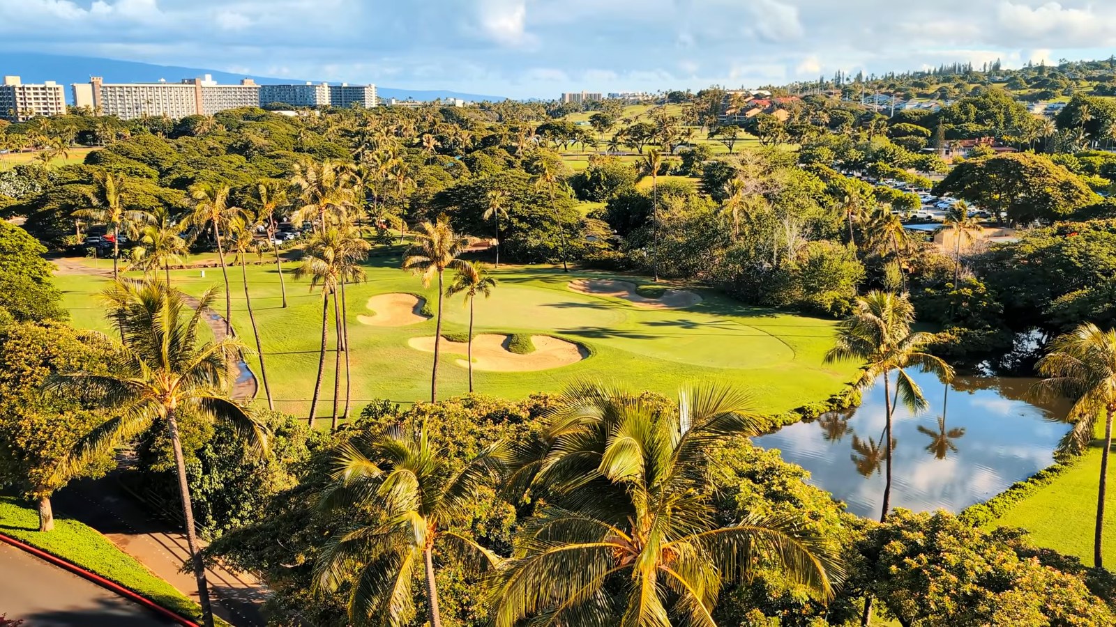 A view over palm trees, a golf course fairway and a pond toward the mountains from the Hyatt Regency Maui.