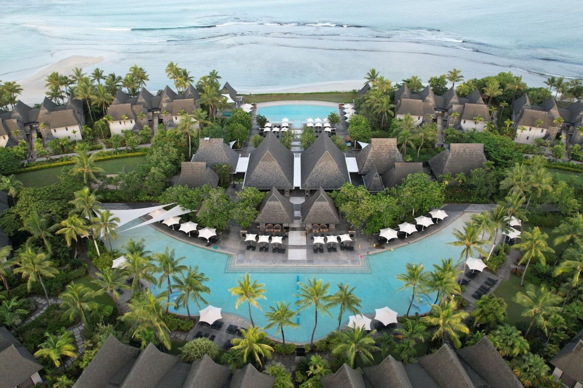 Aerial view of InterContinental Fiji Golf Resort & Spa with both pools, the thatched-roof central buildings, villas and the beach beyond.