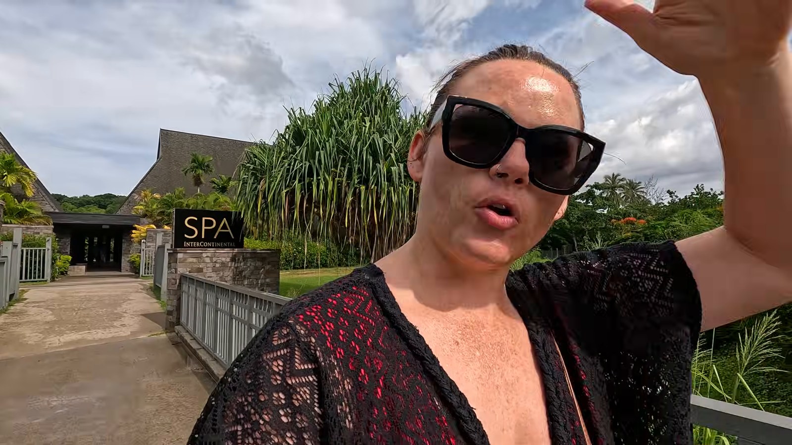 A woman in sunglasses outside the resort spa entrance, with the 'SPA InterContinental' sign and thatched-roof building behind.