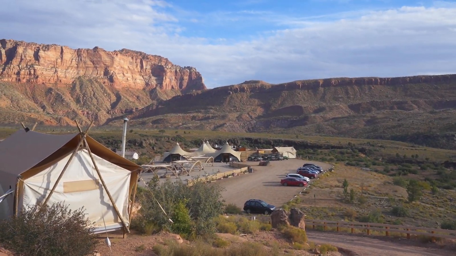 A canvas tent on a hillside above the Under Canvas Zion camp, with red rock cliffs and desert scrub beyond.